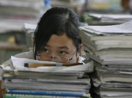 Female student behind a stack of papers